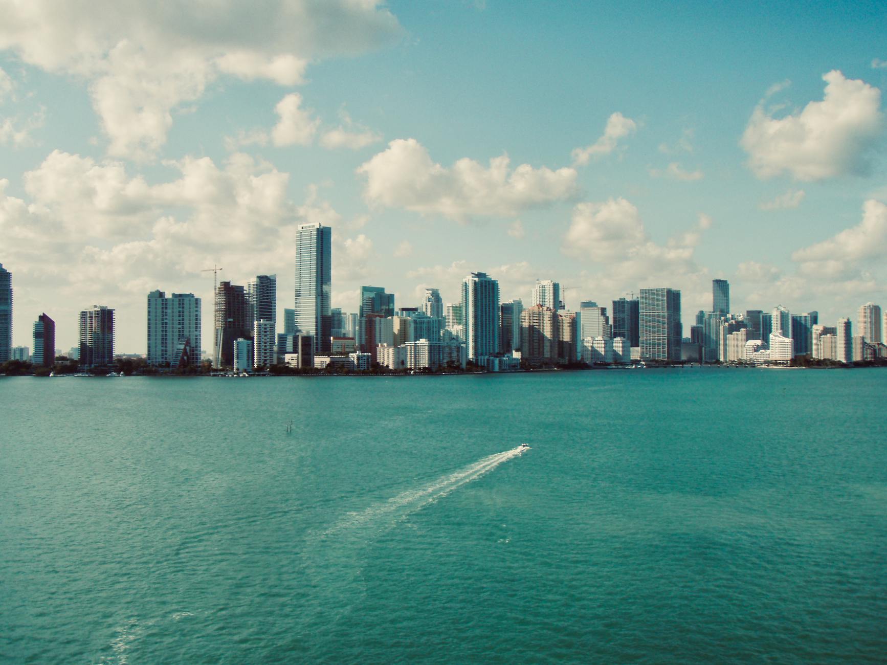 Aerial view of Miami downtown skyline with skyscrapers reflecting over blue Biscayne Bay waters
