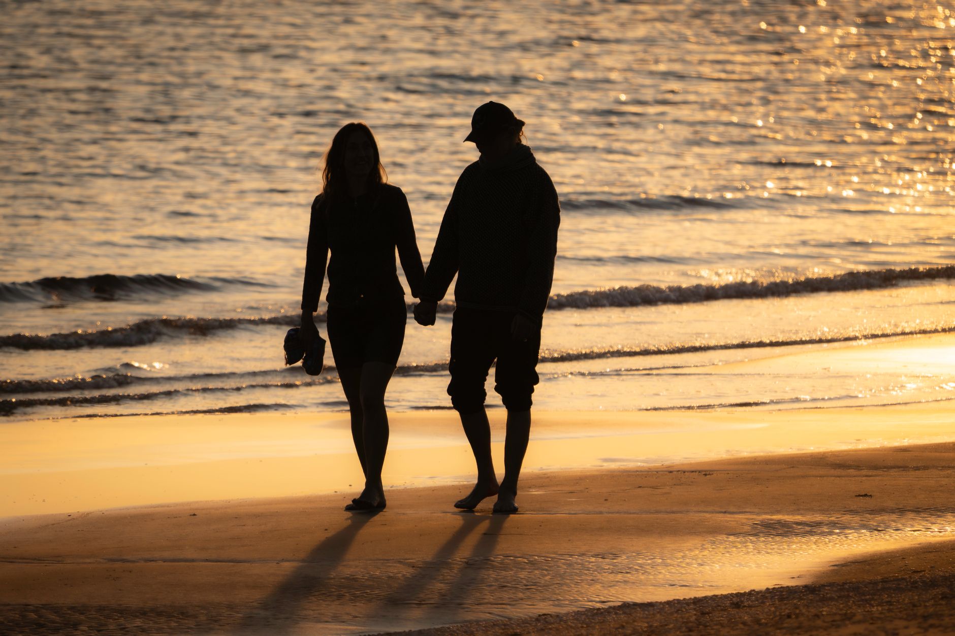 Couple walking hand in hand on a beach at sunset