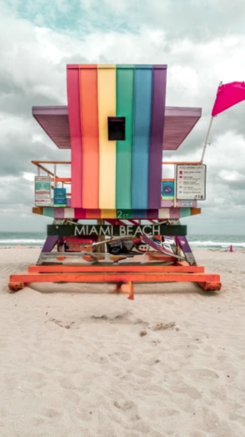 The rainbow-striped lifeguard tower at 12th Street on Miami Beach, with a red warning flag flying