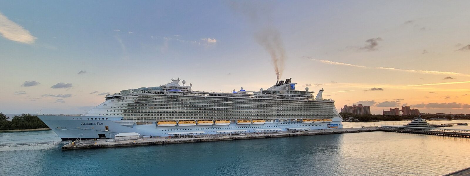 A large Royal Caribbean ship docked at Nassau Cruise Port at sunset with the Atlantis resort in the background