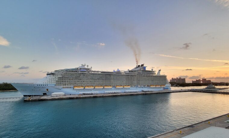 A large Royal Caribbean ship docked at Nassau Cruise Port at sunset with the Atlantis resort in the background