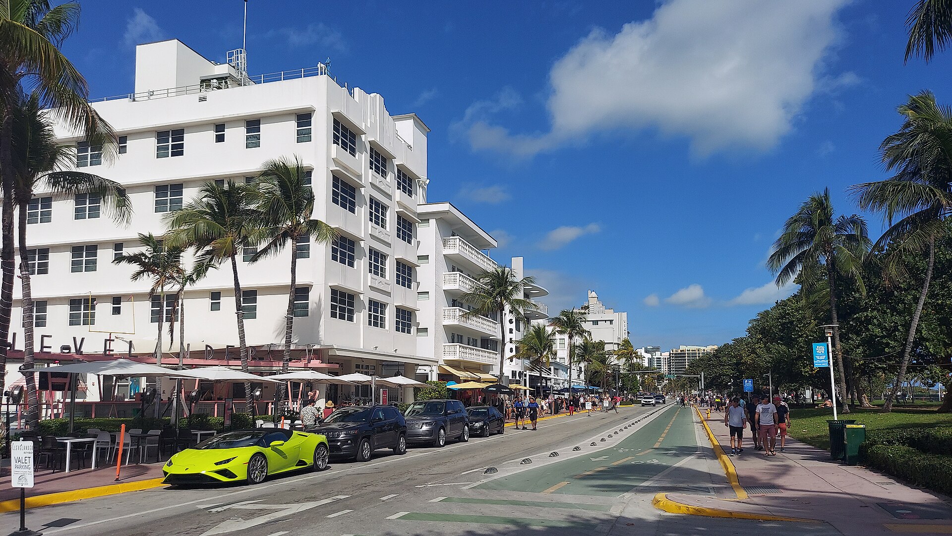 The white Art Deco Clevelander hotel on Ocean Drive with its patio umbrellas, palm trees and a lime-green sports car parked outside