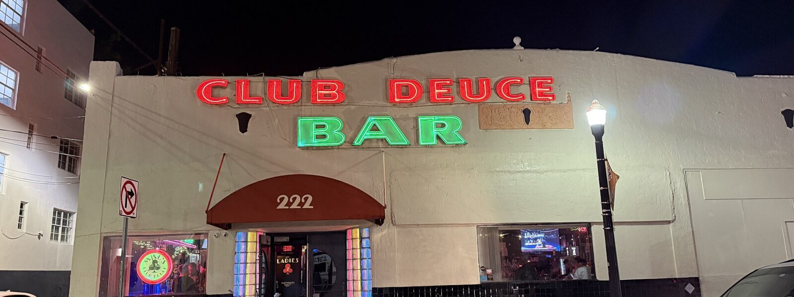 The neon Club Deuce Bar sign glowing red and green above the entrance at 222 14th Street in South Beach at night