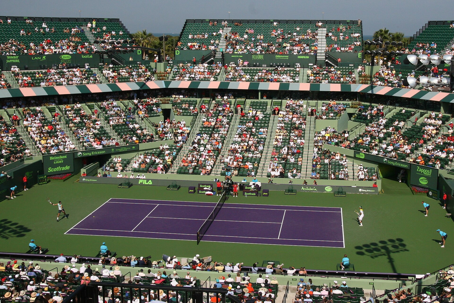 A match on the purple court of the old Crandon Park stadium court on Key Biscayne in 2009, with spectators in hats filling the stands