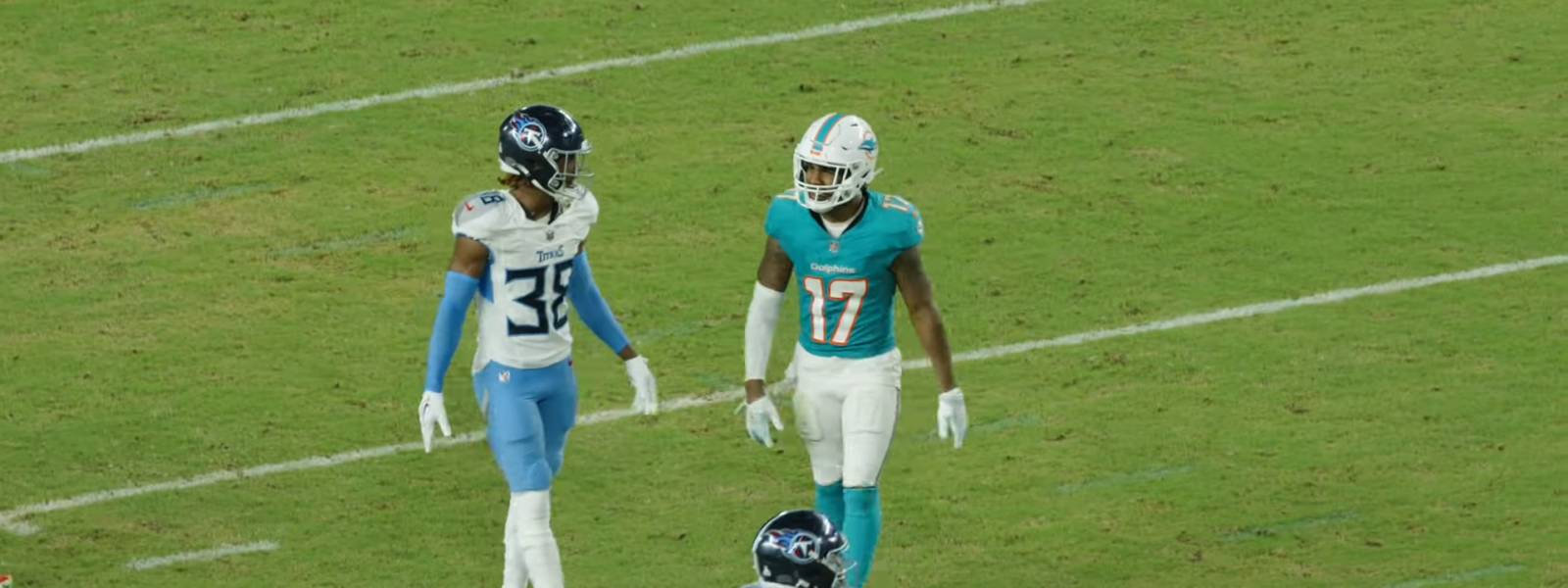 Dolphins receiver Jaylen Waddle in the aqua home jersey lining up against Tennessee Titans defenders on the field at Hard Rock Stadium