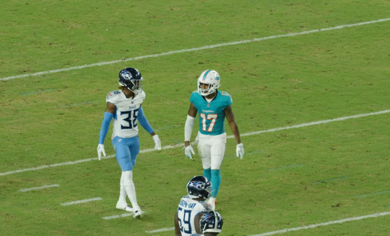 Dolphins receiver Jaylen Waddle in the aqua home jersey lining up against Tennessee Titans defenders on the field at Hard Rock Stadium