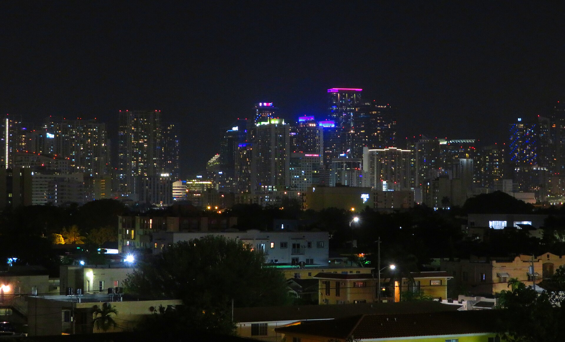 Downtown Miami's towers lit up at night, seen from loanDepot park across the low rooftops of Little Havana