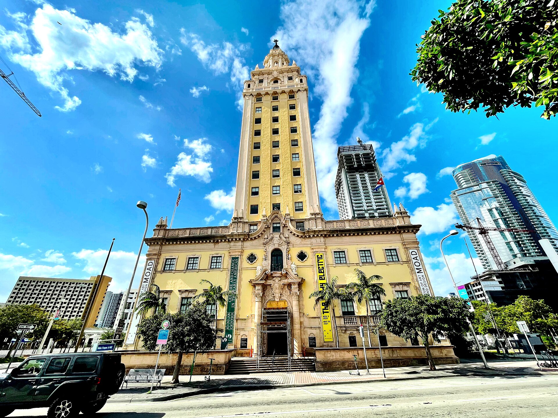 The Freedom Tower in downtown Miami, a cream Mediterranean Revival tower with an ornate entrance and palm trees, against a bright blue sky