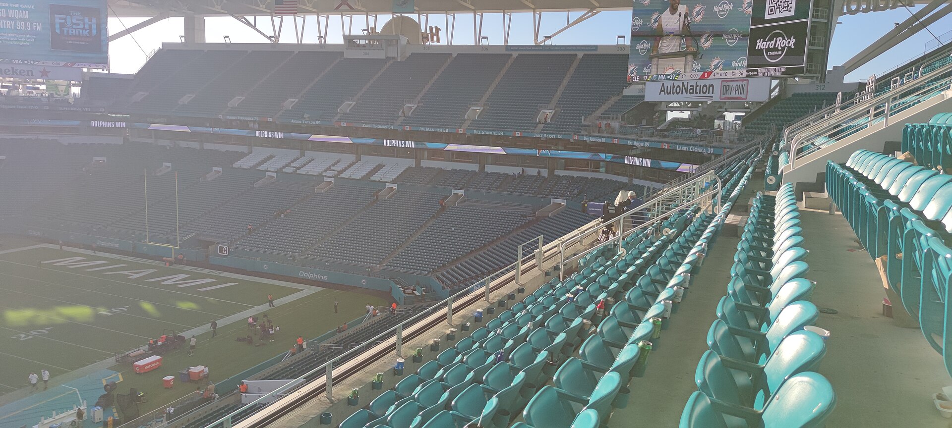 The teal lower bowl of Hard Rock Stadium emptying after a Dolphins game, with the shade canopy overhead