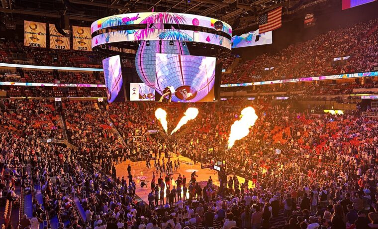 Flames shooting up beside the court during pre-game introductions at a packed Kaseya Center, with the 2006, 2012 and 2013 championship banners overhead