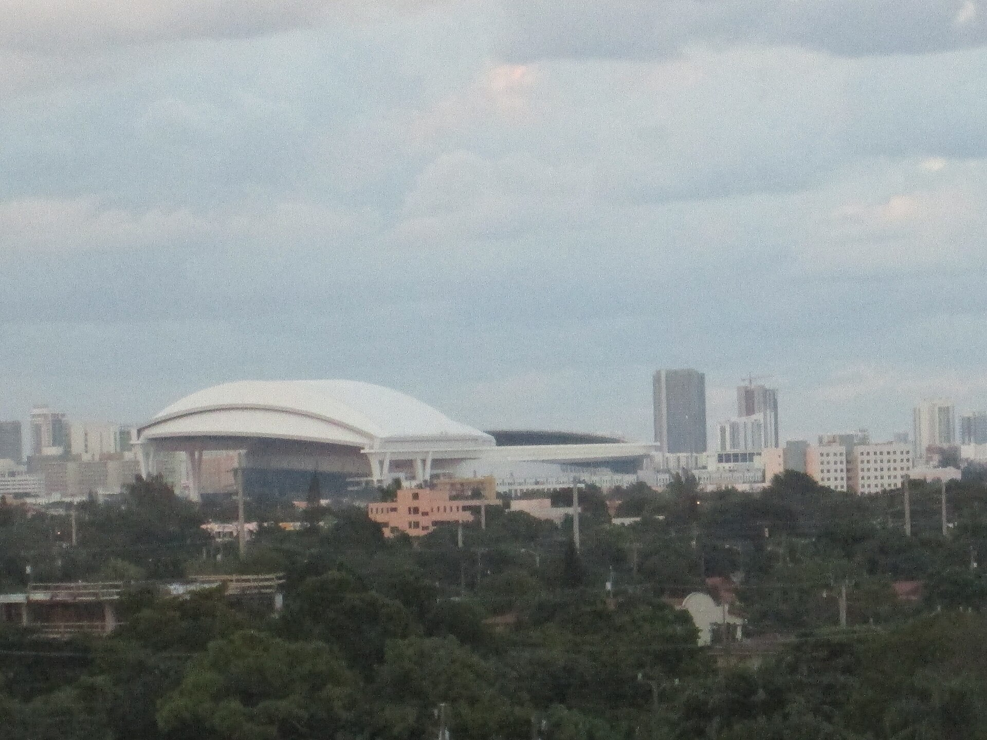 The white retractable roof of loanDepot Park rising above the low-rise rooftops of Little Havana