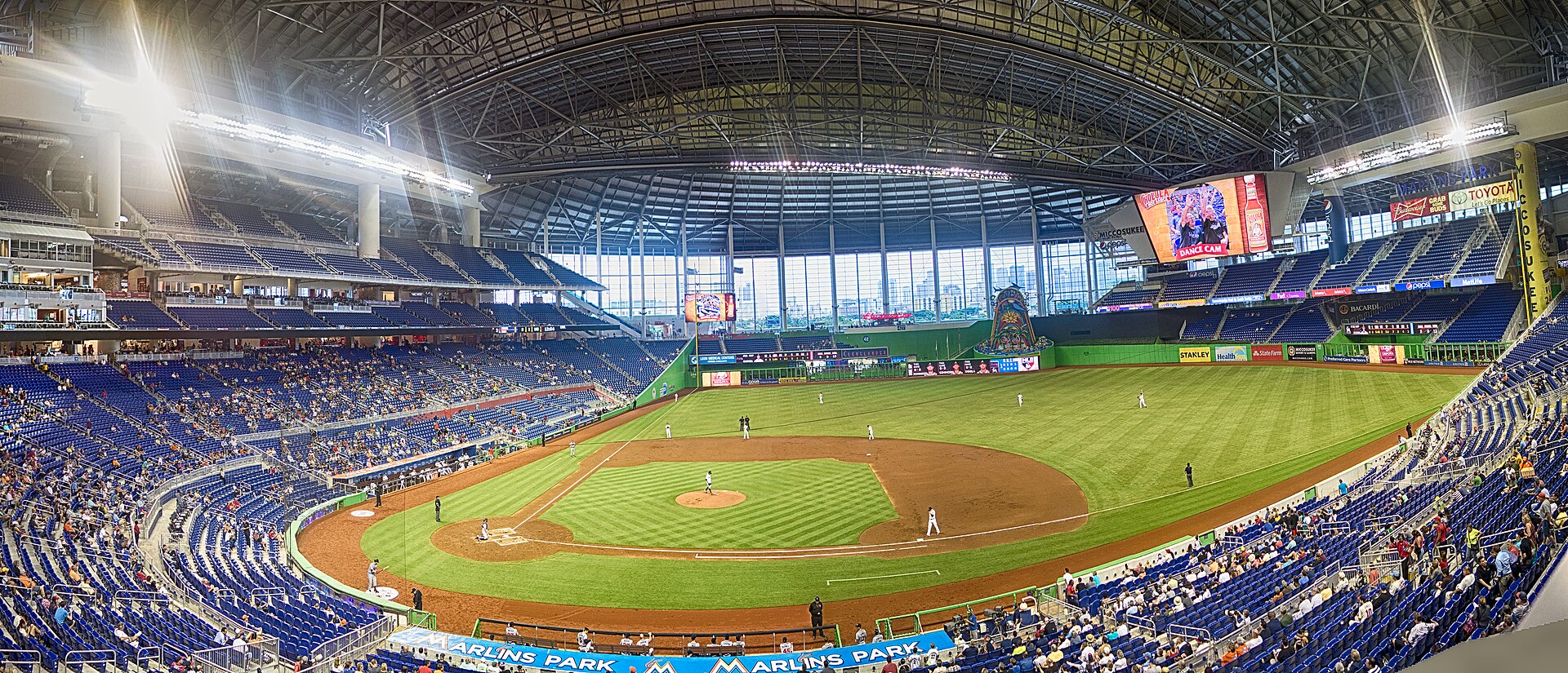 A panoramic view inside Marlins Park in its early years, with the roof closed, green outfield walls and the home run sculpture in center field