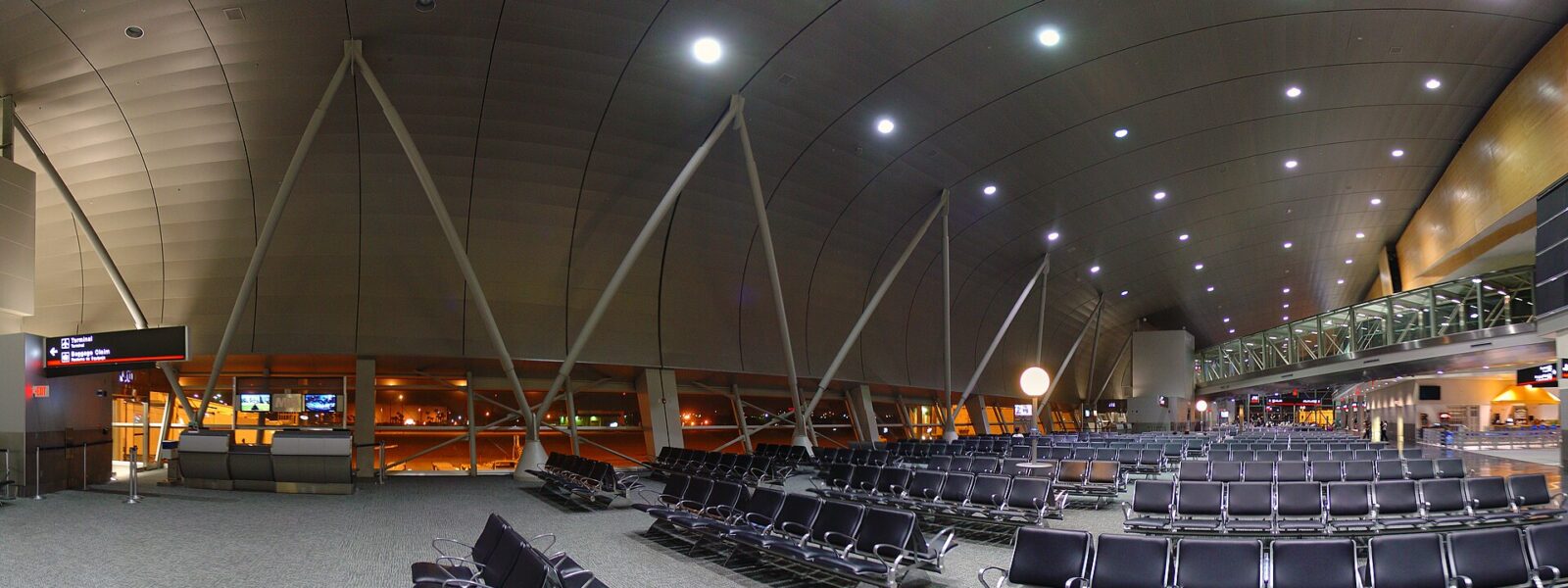 The vaulted concourse of a Miami International Airport terminal with rows of empty seating