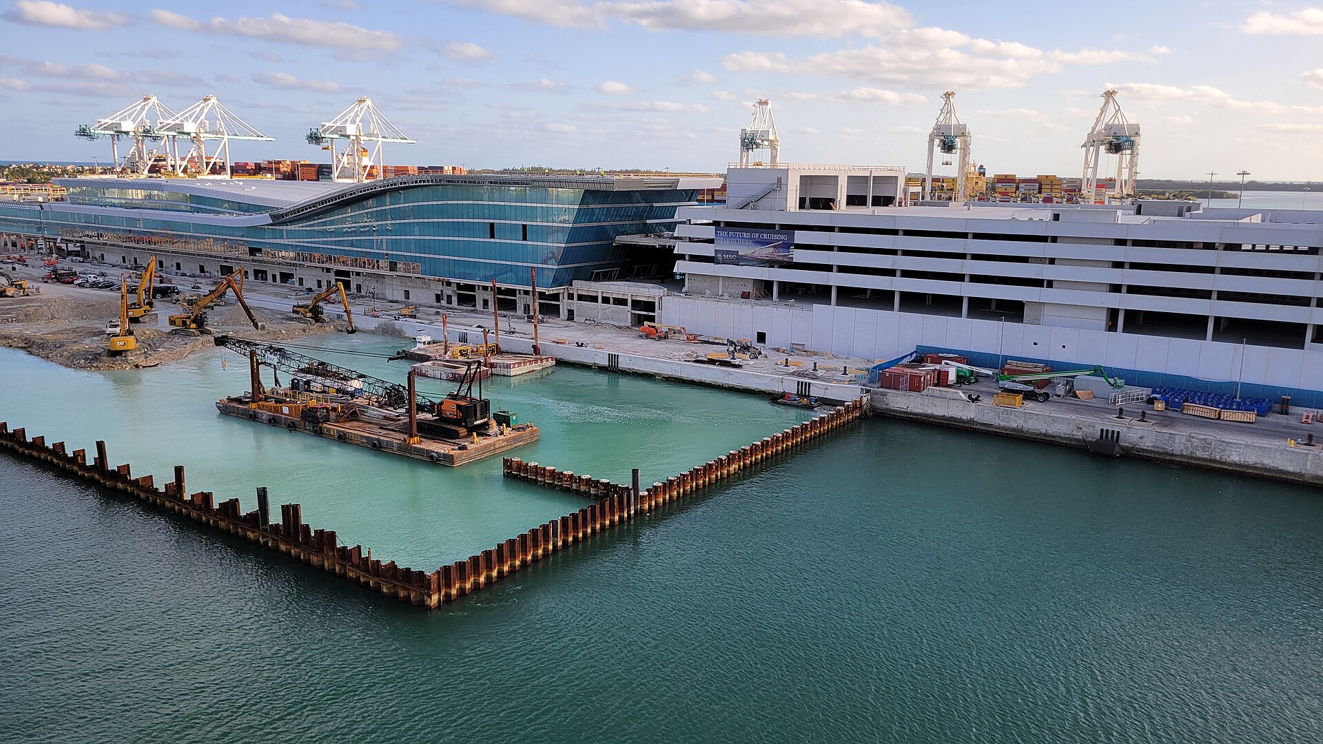 MSC's cruise terminal at PortMiami mid-construction in March 2024, with excavators, a piling barge and an unfinished parking structure