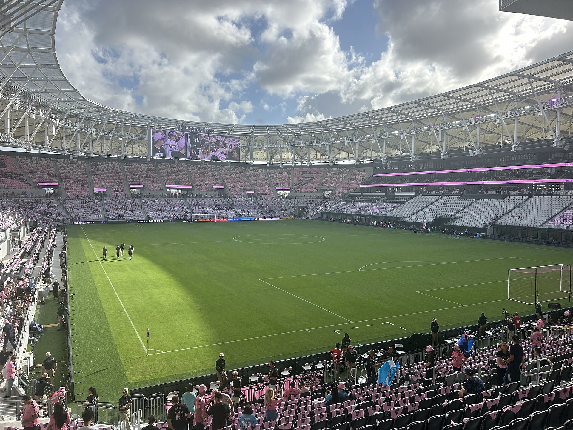 The pitch at Nu Stadium seen from the lower level, with the pink and black seats of both tiers and the canopy roof overhead