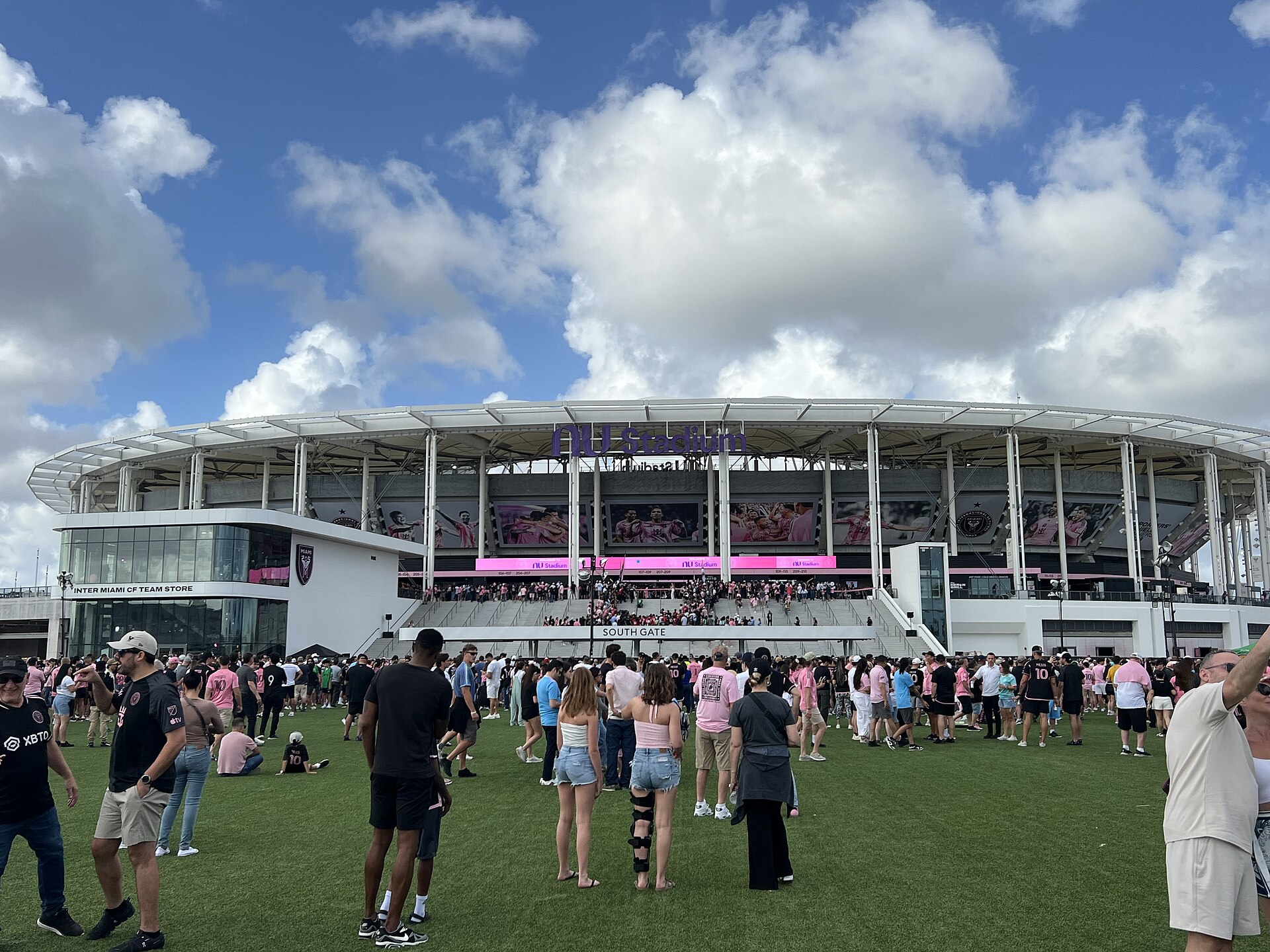 Crowds of fans in pink and black Inter Miami shirts gathered on the lawn outside the Nu Stadium South Gate before a match