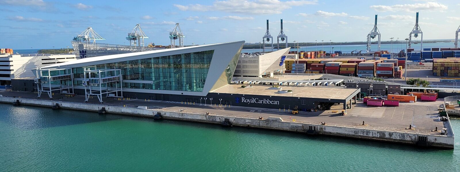 The angular glass Royal Caribbean Terminal A building at PortMiami seen from the water
