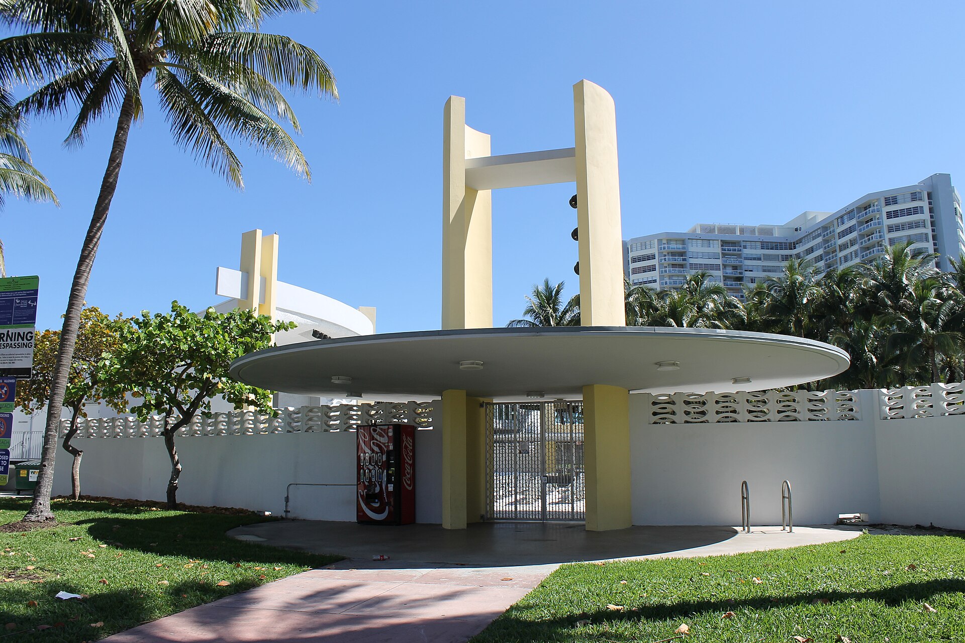 North Shore Bandshell in North Beach, Miami Beach, with an oval canopy, tall yellow piers, white screen walls and palms.