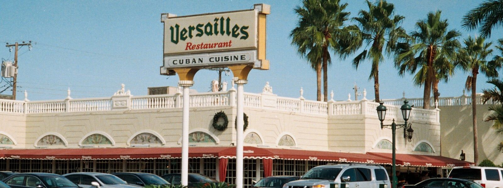 Versailles Restaurant on Miami’s Calle Ocho, with a tall Cuban cuisine sign, red awnings and palms.